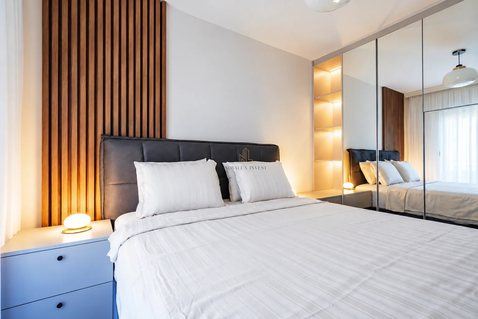 Modern bedroom with a double bed, wooden wall panels and a built-in mirrored wardrobe.