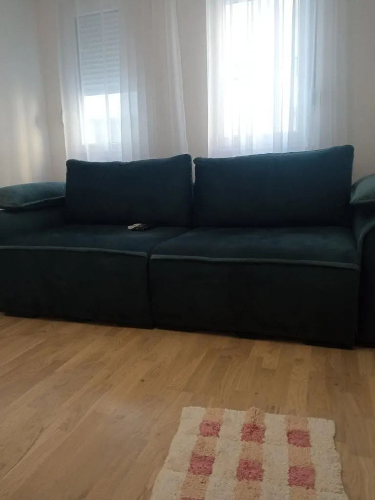 Dark green sofa in the living room with wooden flooring.