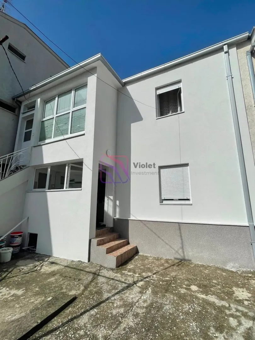 View of the exterior of the house with a white facade and yard.