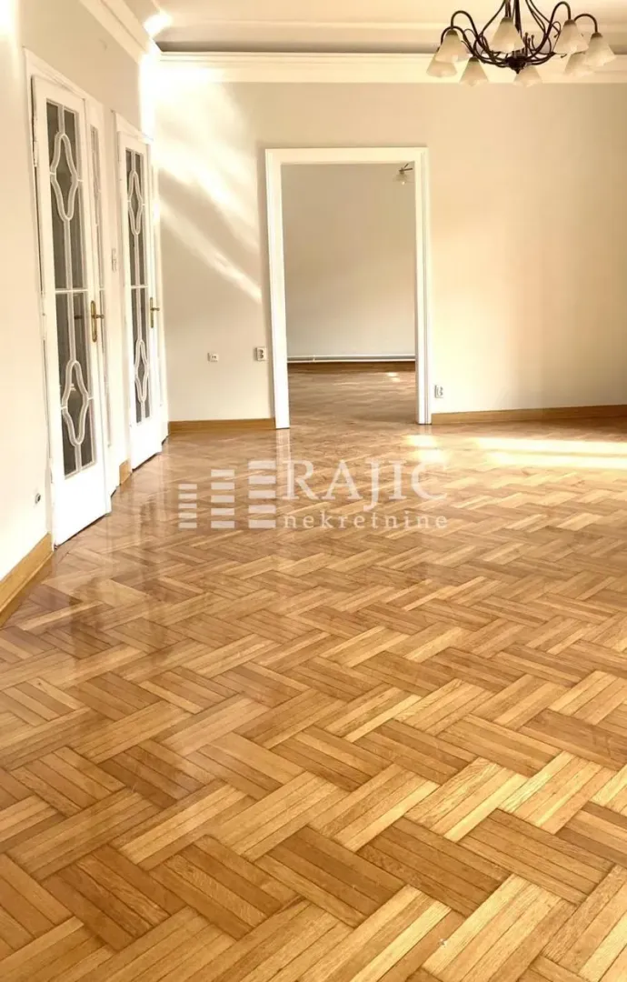 Empty room with parquet flooring and white doors.