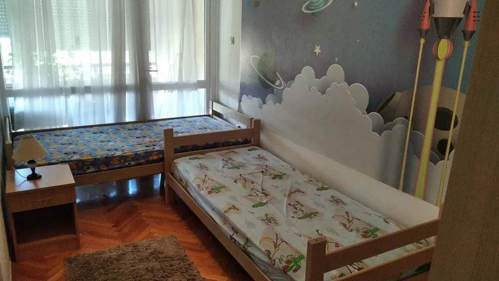 Dječija soba sa dva kreveta i tapetama sa temom svemira.