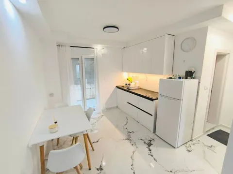 Modern white kitchen with dining area and refrigerator. - image 5