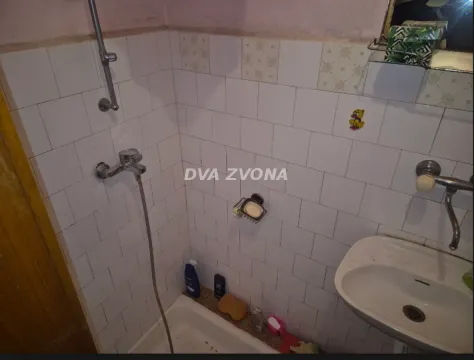 Kupatilo sa tuš kabinom i umivaonikom obloženo belim pločicama. - image 18