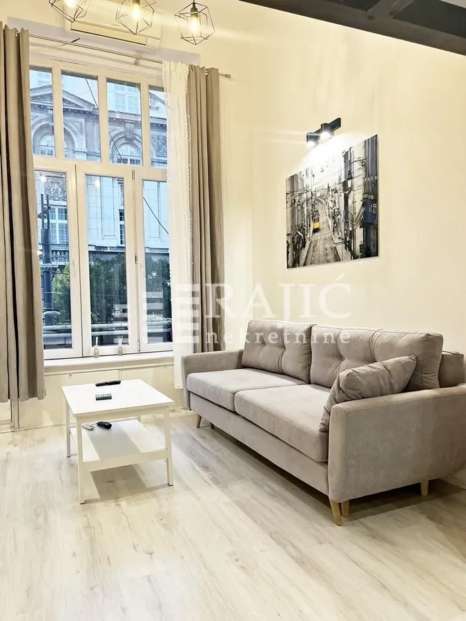 Living room with a sofa, coffee table, and a large window.