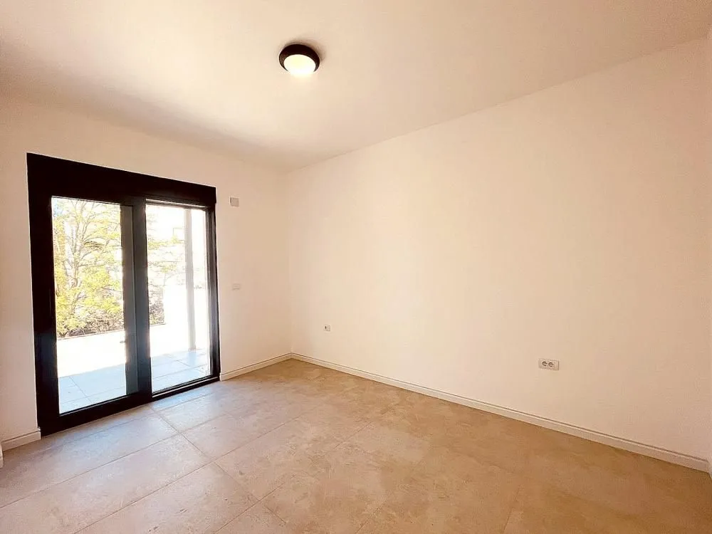 Empty room with tiled floors and glass doors leading to the terrace.