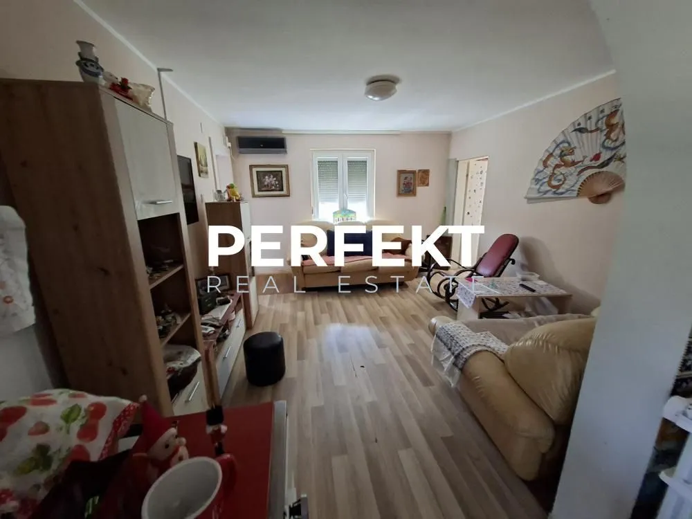 Dnevna soba sa garniturom za sedenje i drvenim nameštajem.