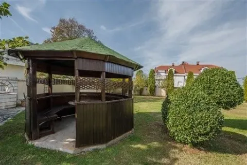 A wooden gazebo in a spacious green yard. - image 30