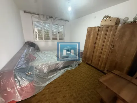 Bedroom with a bed covered in protective plastic and a wooden wardrobe. - image 4