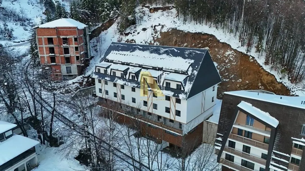 Pogled iz vazduha na stambenu zgradu okruženu snegom.
