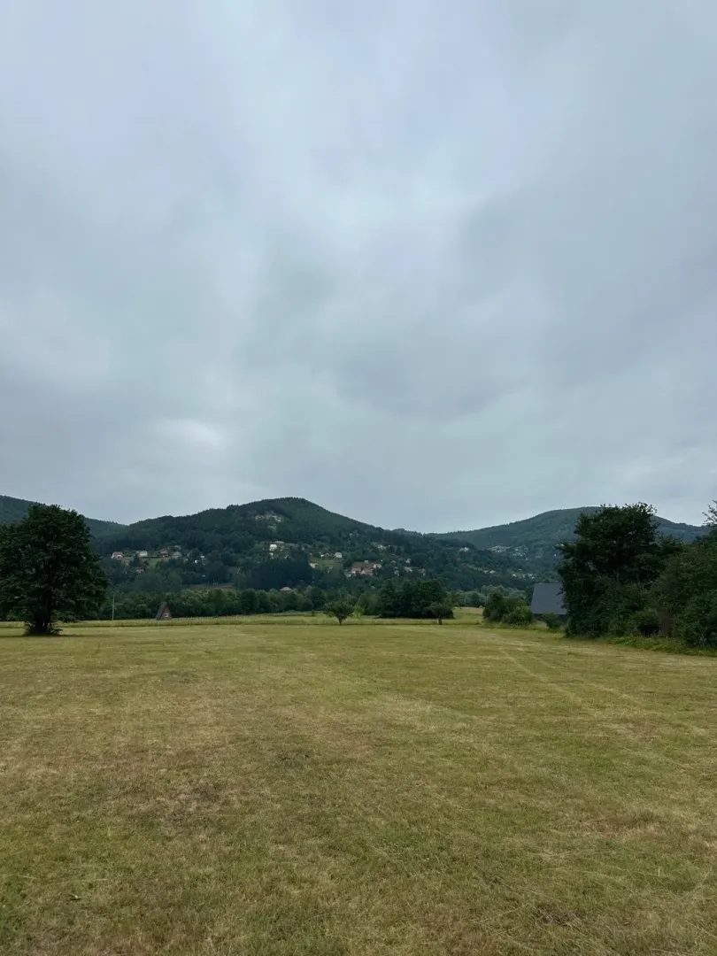 Pogled na prostranu livadu i okolna brda.