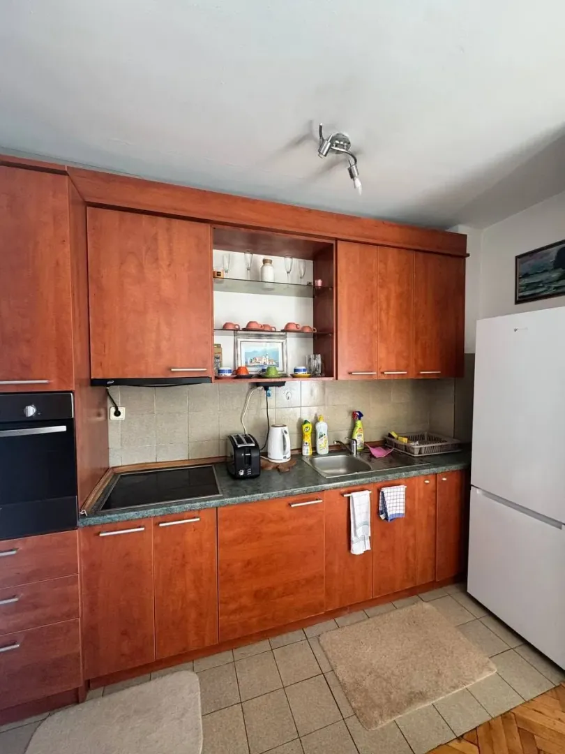 Wooden kitchen cabinets with built-in appliances and a refrigerator.