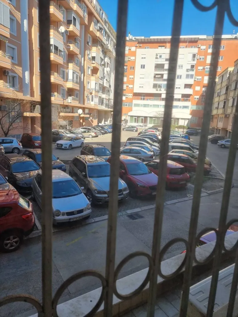View from the window overlooking a shared parking lot and surrounding apartment buildings.