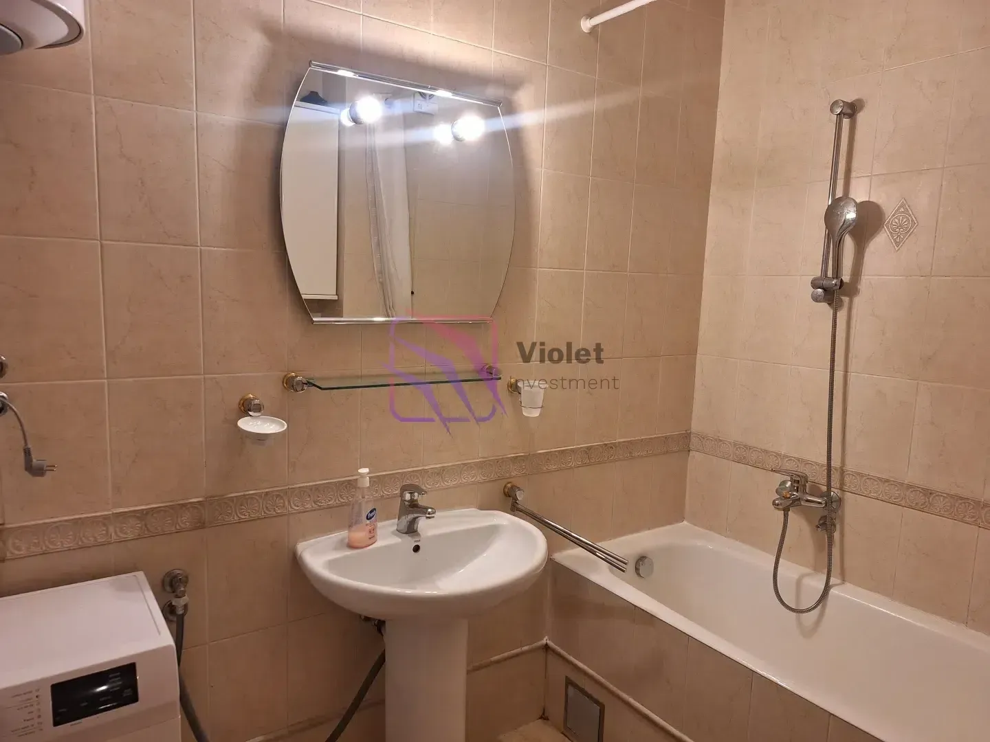 Bathroom equipped with a washbasin, bathtub, mirror, and washing machine.