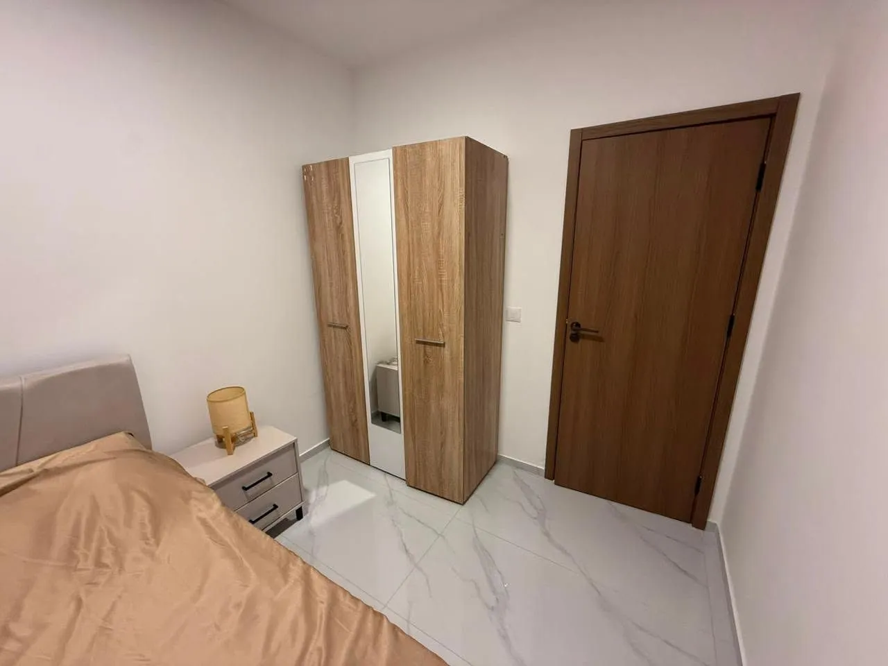 Bedroom with a bed, wooden wardrobe, and a door.