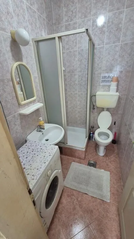 Smaller bathroom with a shower cabin, washbasin, toilet, and washing machine.