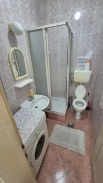 Smaller bathroom with a shower cabin, washbasin, toilet, and washing machine. - image 9