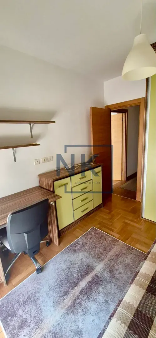 Smaller bedroom with a bed, desk, and shelves.