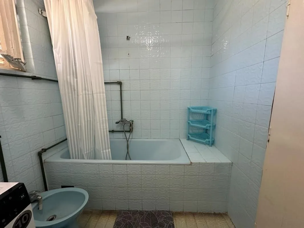 Bathroom with a bathtub, shower curtain, and blue sanitary ware.
