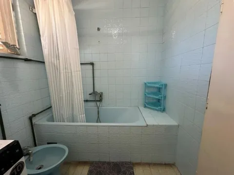 Bathroom with a bathtub, shower curtain, and blue sanitary ware. - image 2