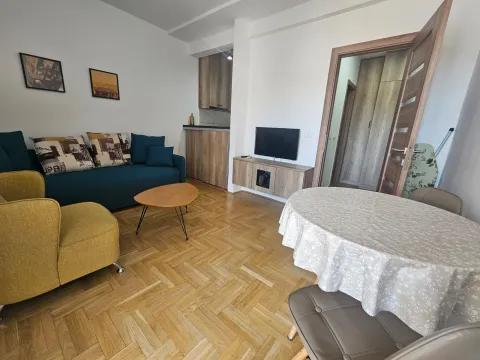 Dnevna soba sa garniturom, trpezarijskim stolom i kuhinjskim elementima u pozadini. - image 4
