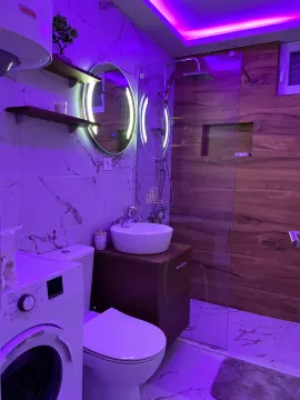 Modern bathroom with a walk-in shower, washbasin, washing machine, and LED lighting. - image 11