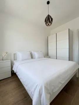 Spavaća soba sa bračnim krevetom, bijelim ormarom i noćnim stočićima. - image 5
