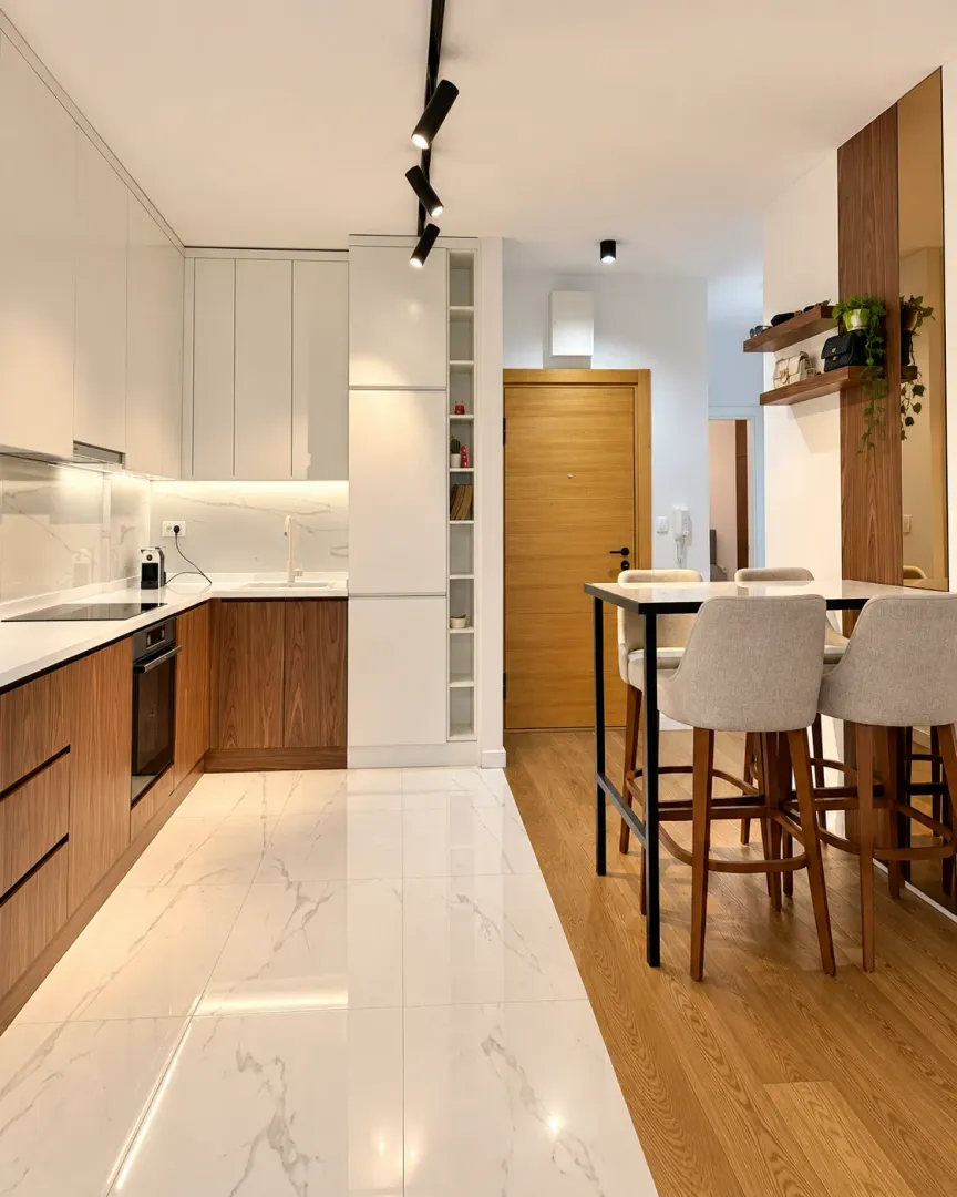 Modern kitchen with white and wooden cabinetry and a dining table.