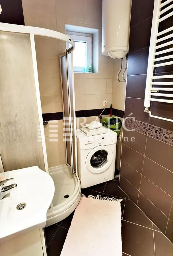 Small bathroom with a shower cabin and a washing machine.