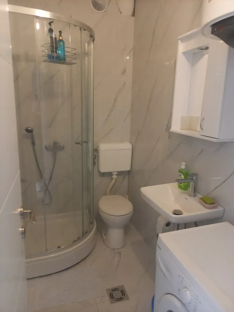 A small bathroom with a shower cabin, toilet, and sink.