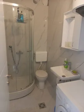 A small bathroom with a shower cabin, toilet, and sink. - image 3