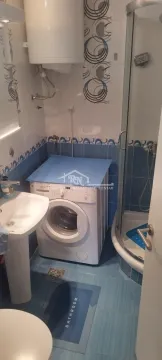 Bathroom equipped with a washbasin, shower cabin, washing machine, and water heater. - image 8