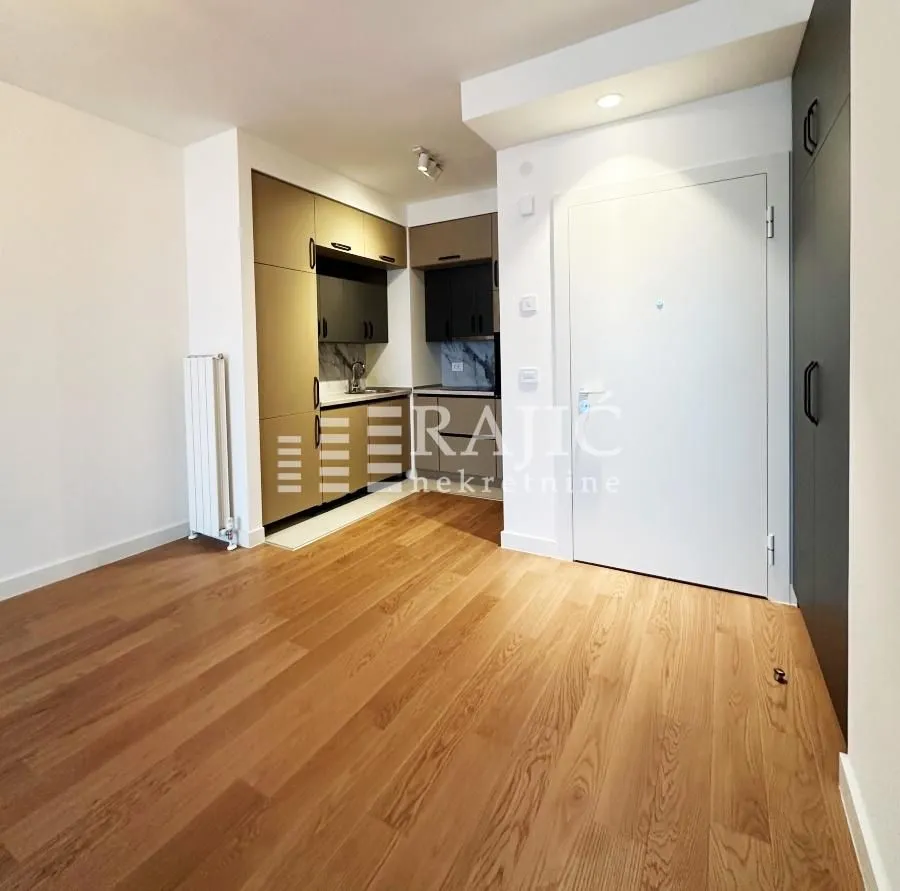 Living room with a view of the entrance door and a small kitchen.