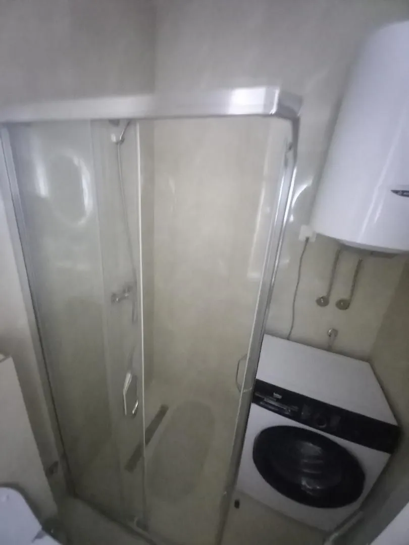 Small bathroom with a shower cabin and a washing machine.