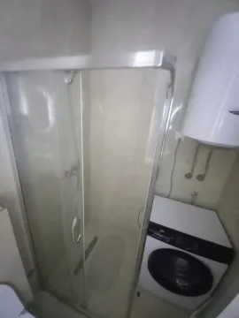 Small bathroom with a shower cabin and a washing machine. - image 8
