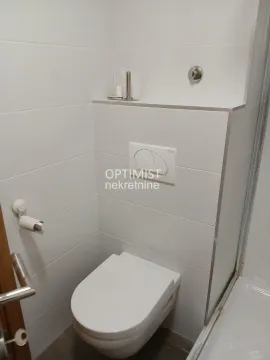 Moderno opremljeno kupatilo sa WC šoljom i belim pločicama. - image 7