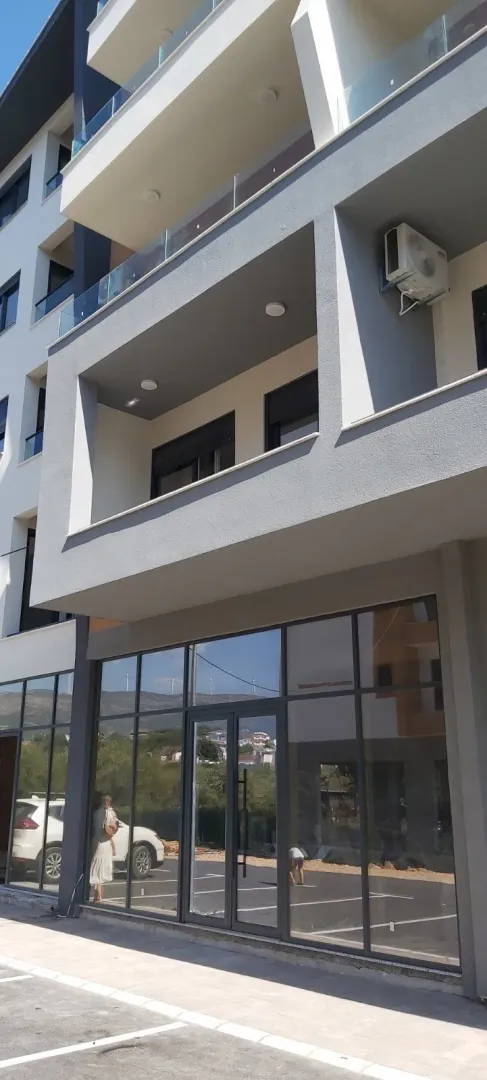 Eksterijer moderne stambene zgrade sa balkonom i poslovnim prostorom u prizemlju.