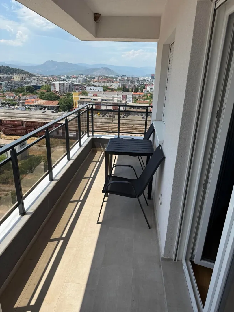 Namtještena terasa sa stolom i stolicama i pogledom na grad.