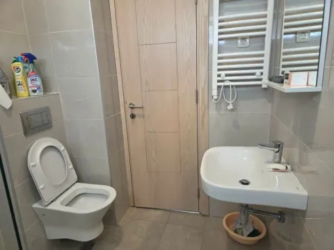 Smaller bathroom with a sink, toilet, and wooden door. - image 10