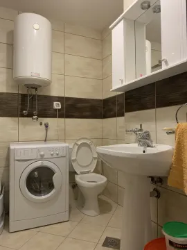 A simple bathroom featuring a washing machine, water heater, and sink. - image 4