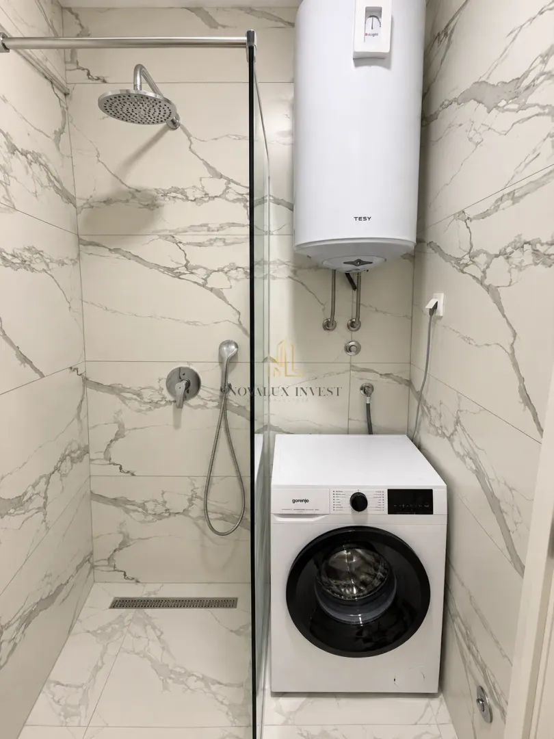 Bathroom with a shower cabin, water heater, and washing machine.