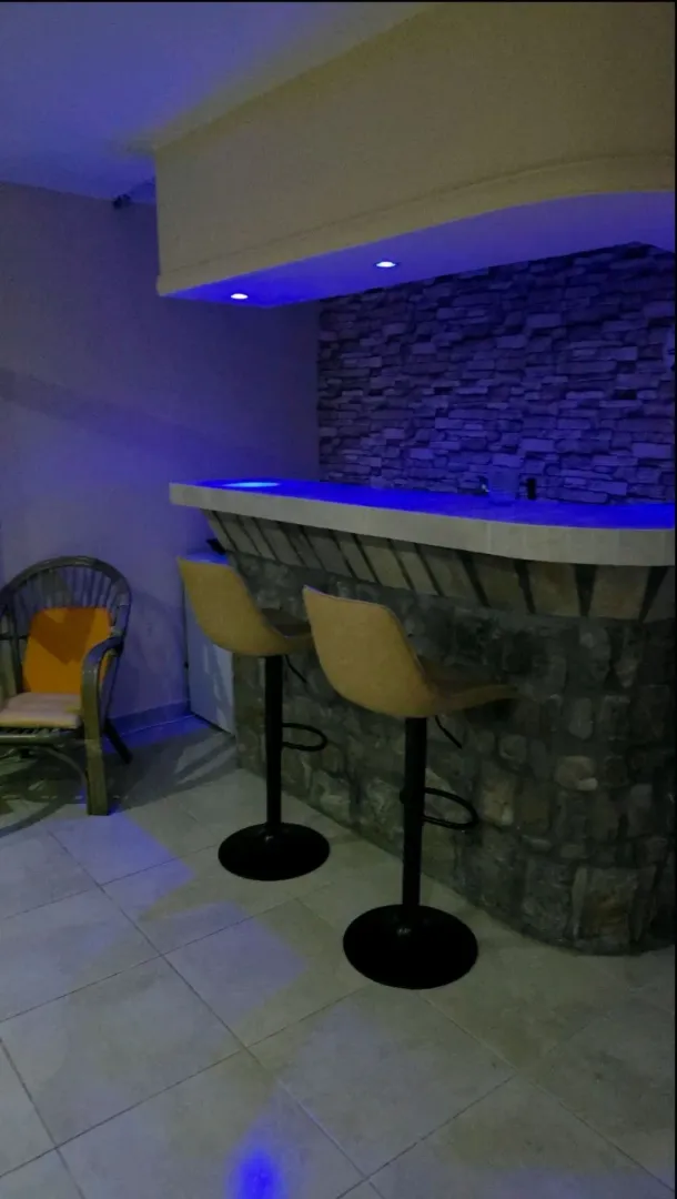 A bar counter with bar stools and a decorative stone wall in the interior.