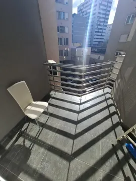 Manji popločani balkon sa metalnom ogradom i jednom stolicom. - image 14