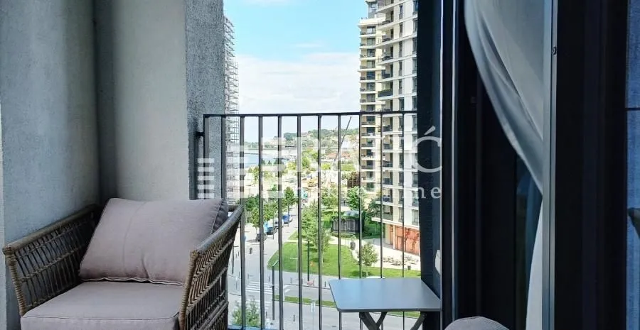 Furnished balcony with an armchair and city view.