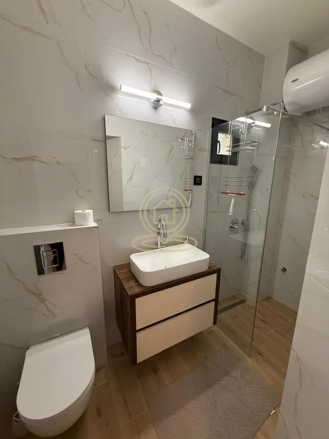 Moderno kupatilo sa tuš kabinom, umivaonikom i ugradnom wc šoljom.