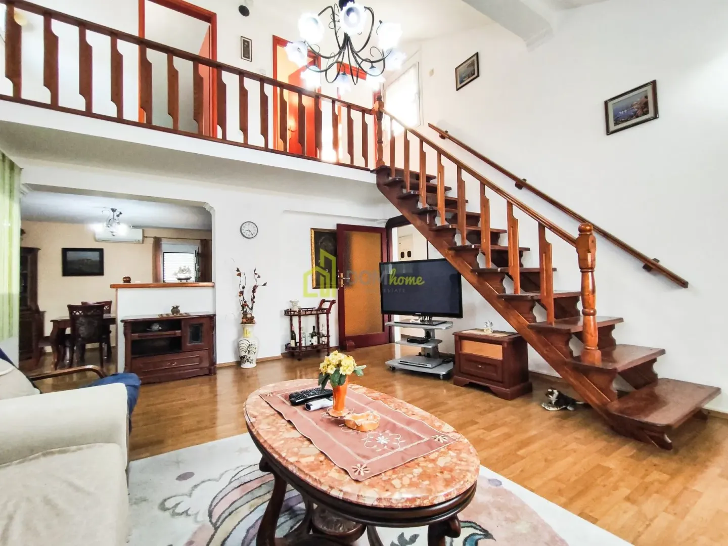 Spacious living room with a wooden staircase and an upper-floor gallery.