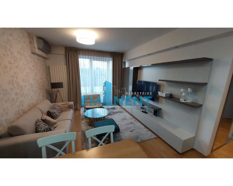 Living room with a sofa, TV unit and dining table.