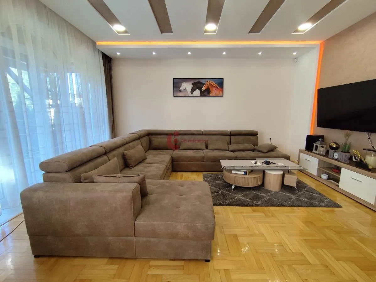 Spacious living room with a large corner sofa, TV, and parquet flooring.