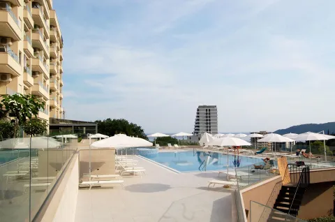Swimming pool with sun loungers and umbrellas next to the residential building. - image 7