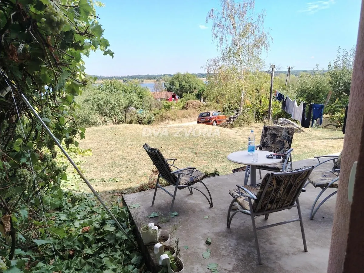 Nameštena terasa sa stolom i stolicama i pogledom na dvorište i prirodu.