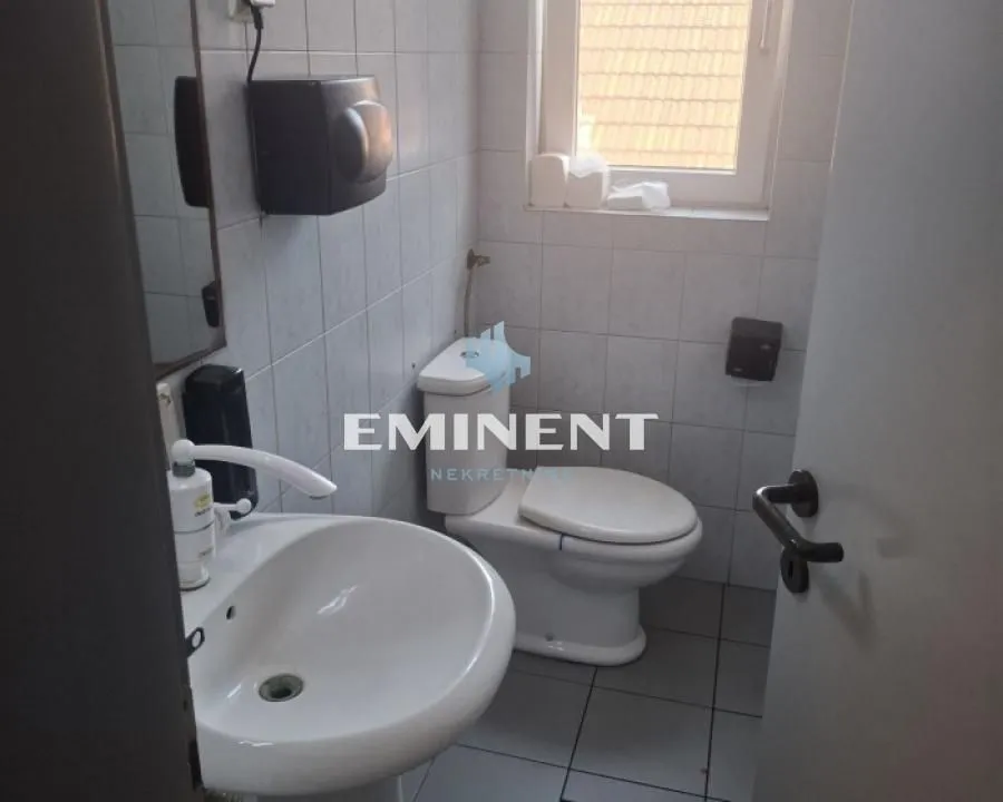 Small tiled bathroom with a sink and a toilet.